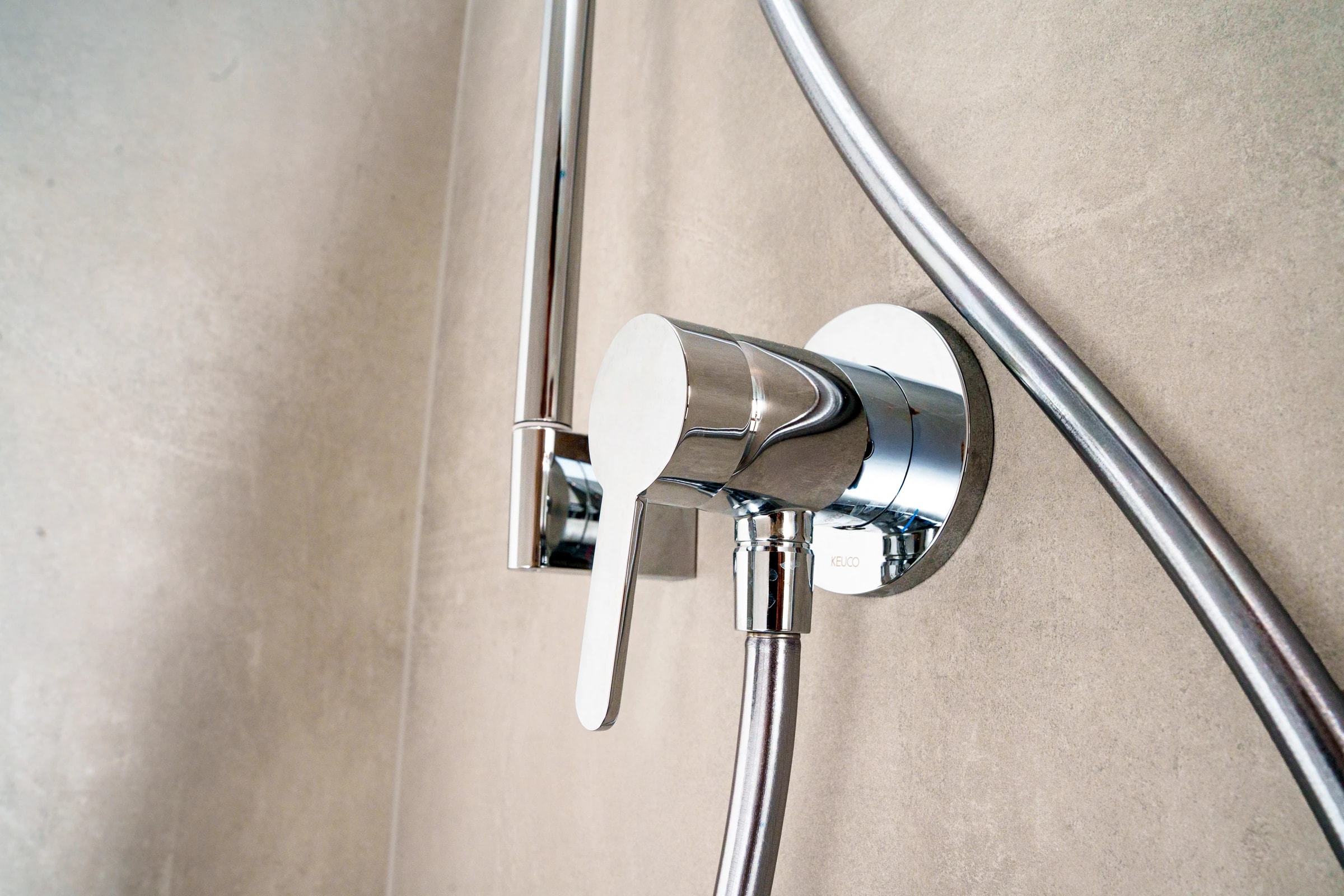 Lichtdurchflutetes Bad mit Wanne, Glasdusche, graubraunen Fliesen und blauen Handtüchern
