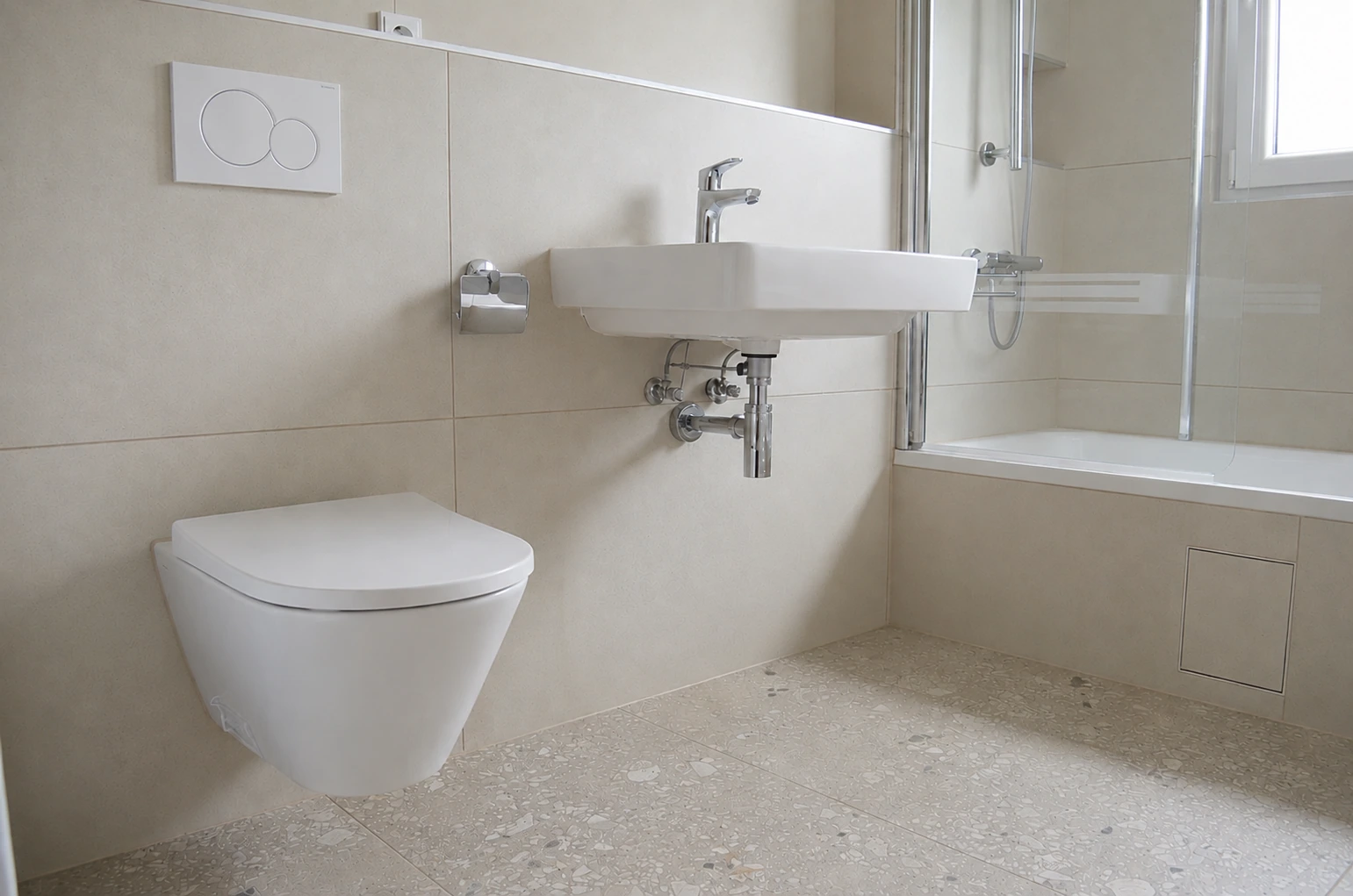 Helles Bad mit beleuchtetem Rundspiegel, Badewanne und terrazzoartigem Boden